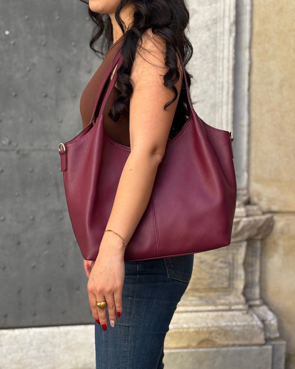 Borsa LOLA in vera pelle martellata, capiente ed elegante, con dettagli in acciaio inox dorato. Dotata di chiusura con zip, interno foderato con tasca interna e tracolla regolabile in vera pelle, è perfetta per un look raffinato e pratico ogni giorno. ALAINCOX Genova Via di fossatello 