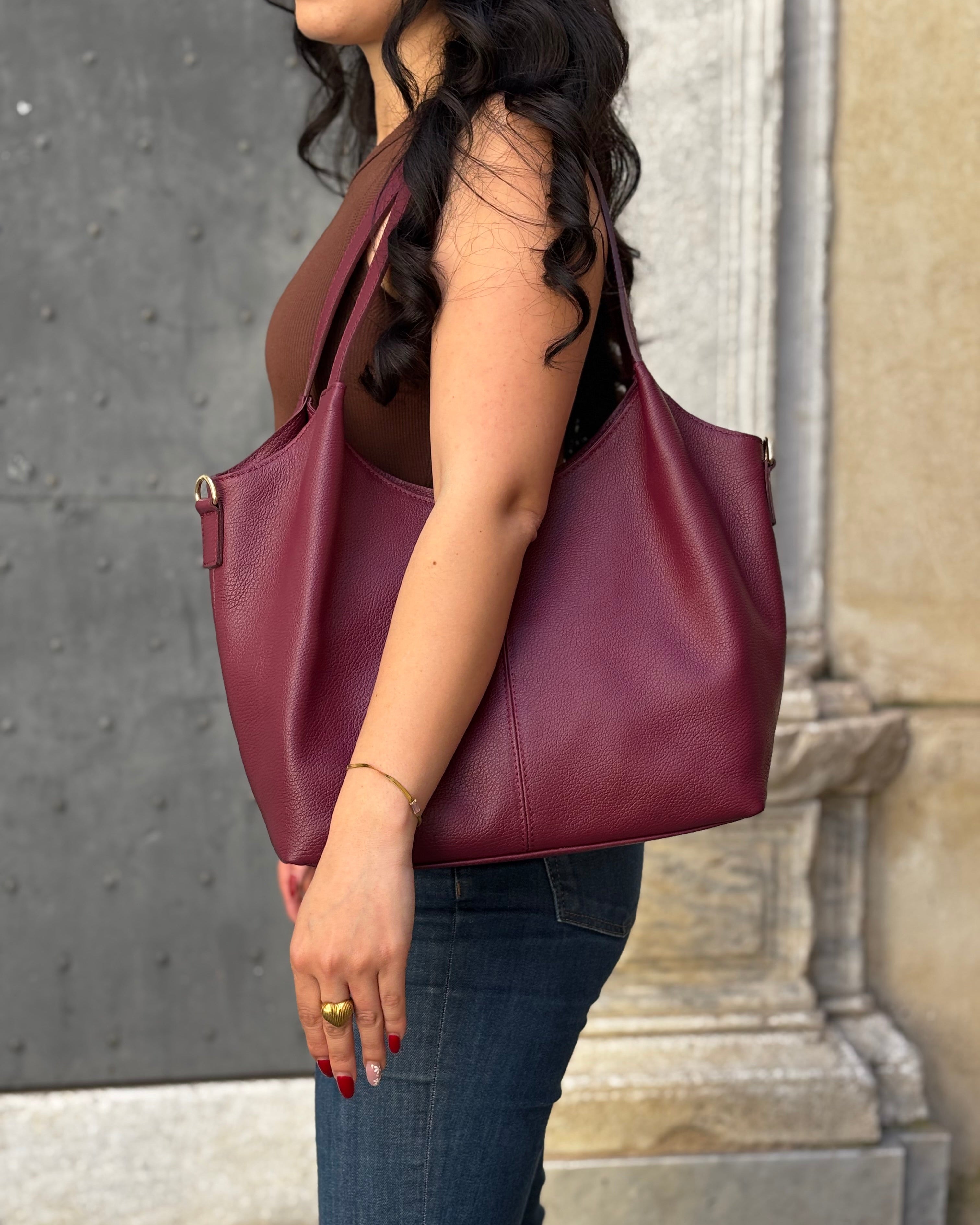 Borsa LOLA in vera pelle martellata, capiente ed elegante, con dettagli in acciaio inox dorato. Dotata di chiusura con zip, interno foderato con tasca interna e tracolla regolabile in vera pelle, è perfetta per un look raffinato e pratico ogni giorno. ALAINCOX Genova Via di fossatello 