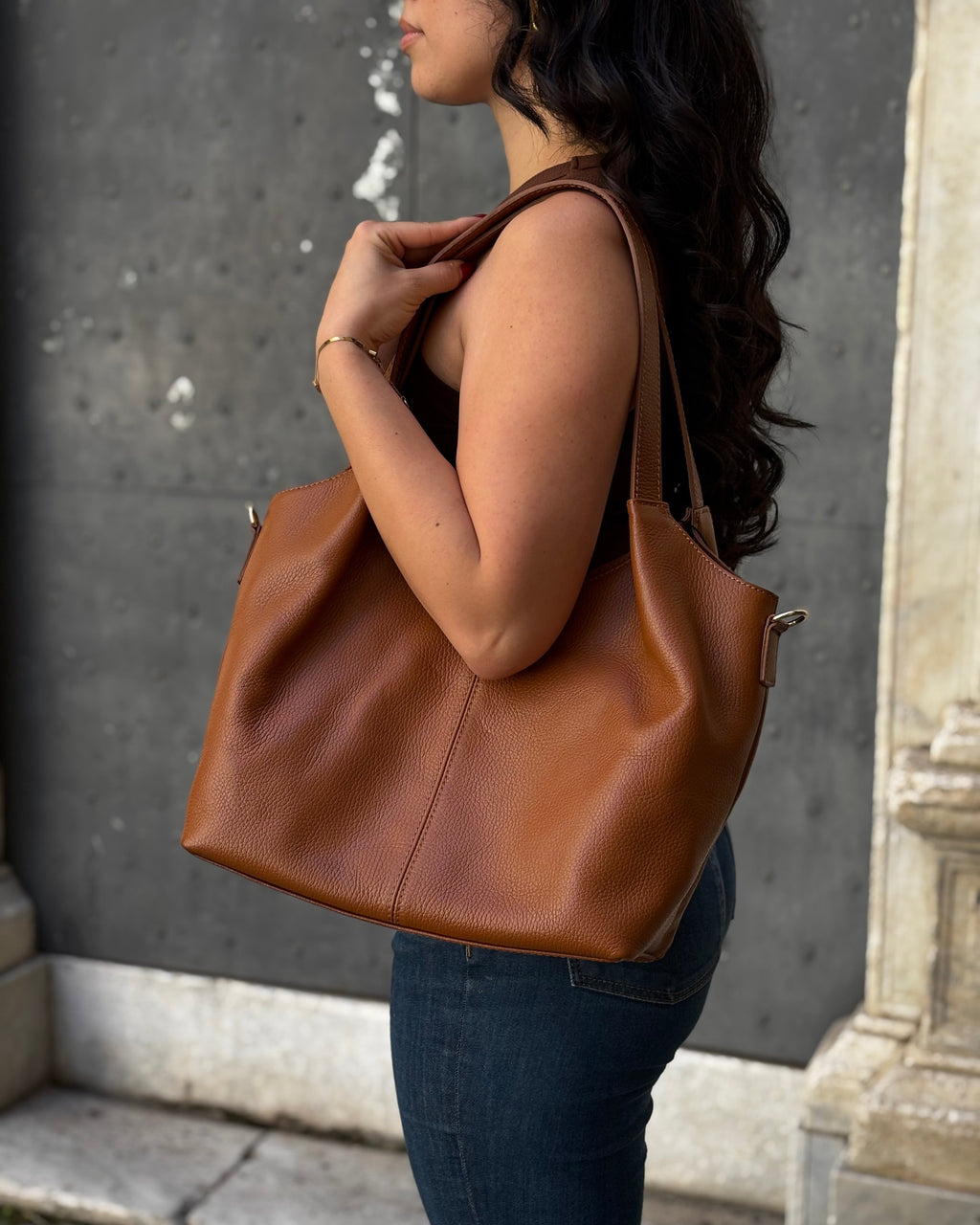 Borsa LOLA in vera pelle martellata, capiente ed elegante, con dettagli in acciaio inox dorato. Dotata di chiusura con zip, interno foderato con tasca interna e tracolla regolabile in vera pelle, è perfetta per un look raffinato e pratico ogni giorno. ALAINCOX Genova Via di fossatello 