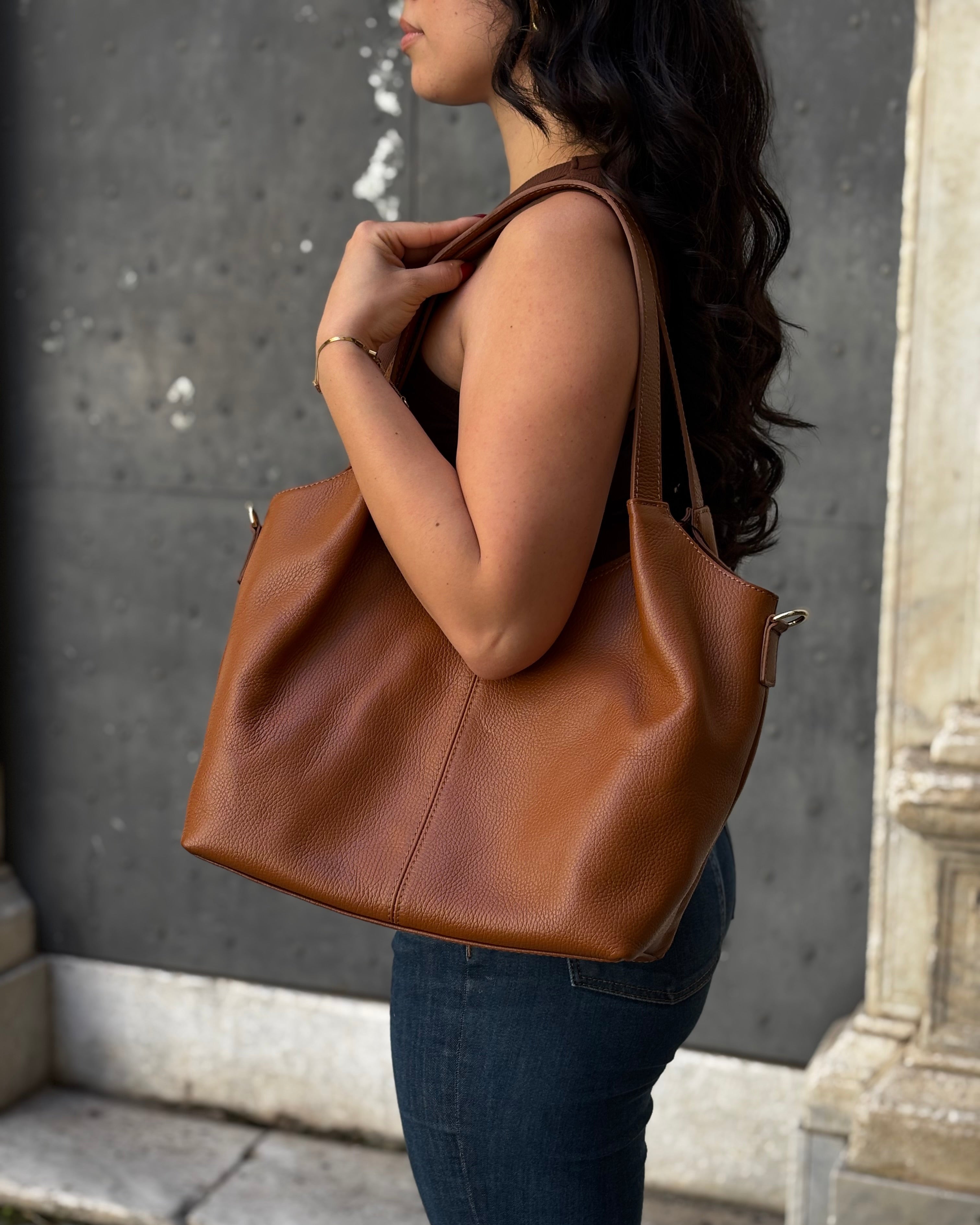 Borsa LOLA in vera pelle martellata, capiente ed elegante, con dettagli in acciaio inox dorato. Dotata di chiusura con zip, interno foderato con tasca interna e tracolla regolabile in vera pelle, è perfetta per un look raffinato e pratico ogni giorno. ALAINCOX Genova Via di fossatello 