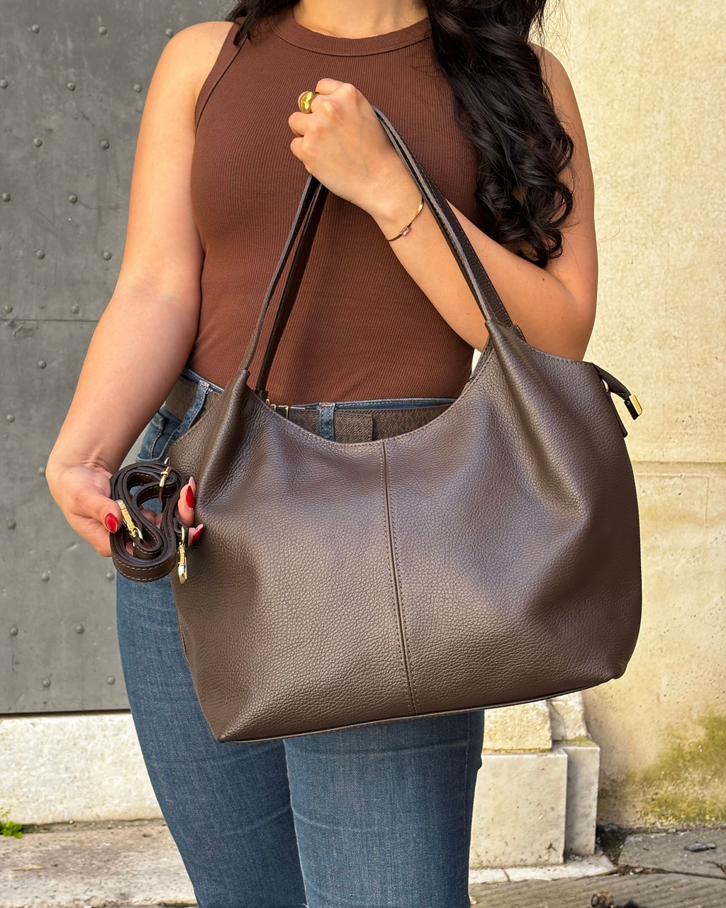 Borsa LOLA in vera pelle martellata, capiente ed elegante, con dettagli in acciaio inox dorato. Dotata di chiusura con zip, interno foderato con tasca interna e tracolla regolabile in vera pelle, è perfetta per un look raffinato e pratico ogni giorno. ALAINCOX Genova Via di fossatello 