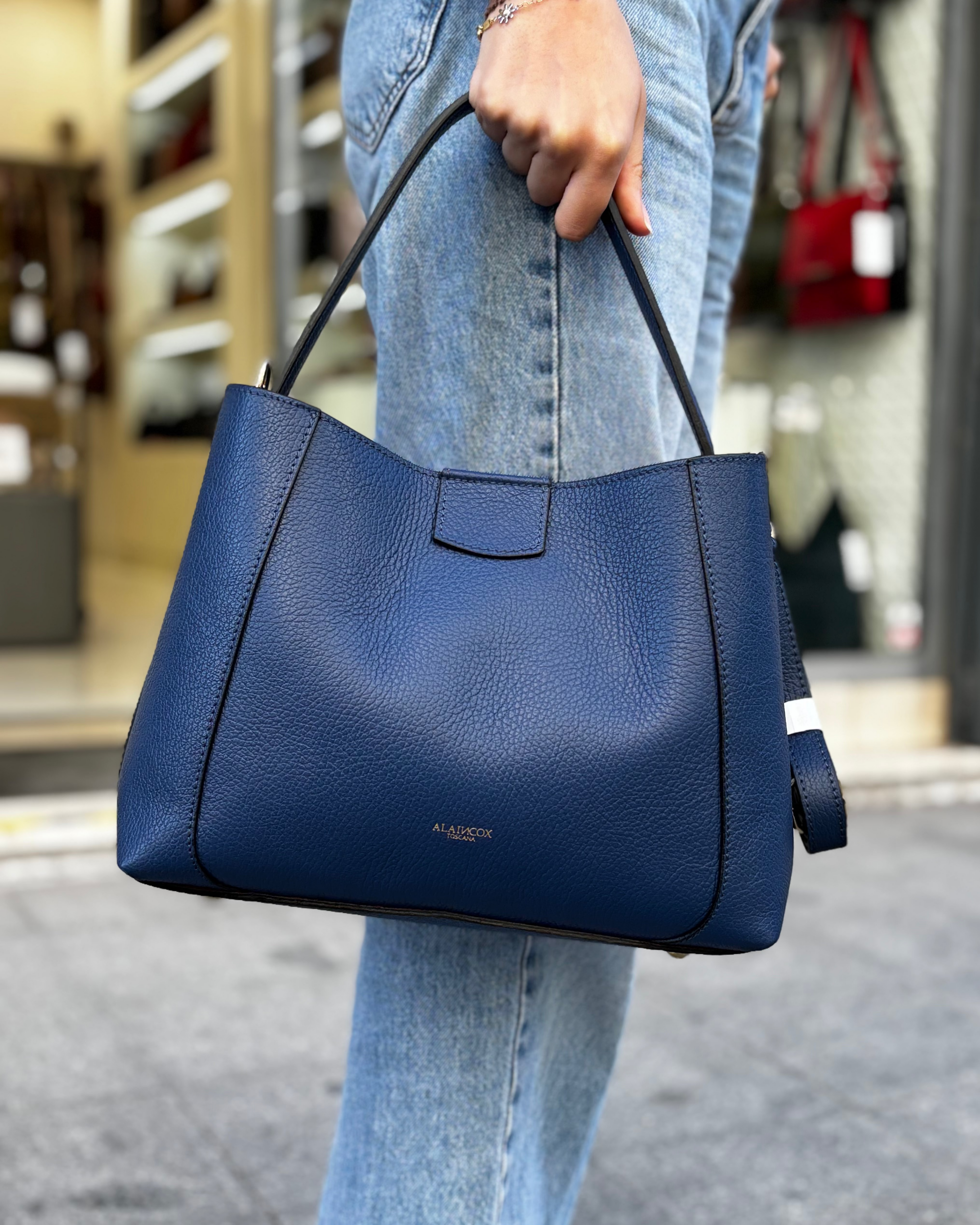 Borsa melina da donna in vera pelle martellata made in italy, colore blu, firmata Alaincox, negozio di Genova, con pochette interna con zip, tracolla regolabile e dettagli in acciaio dorato, elegante e capiente per uso quotidiano.