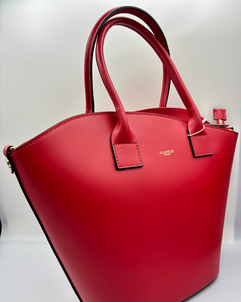 La Borsa Siviglia di ALAINCOX in vera pelle liscia Made in Italy, elegante e spaziosa, con design rosso intenso, chiusura a zip, hardware dorato e tracolla regolabile. Disponibile a Genova nel negozio ALAINCOX in Via di Fossatello. Perfetta per l’uso quotidiano grazie alle dimensioni capienti 38×27×12 cm.