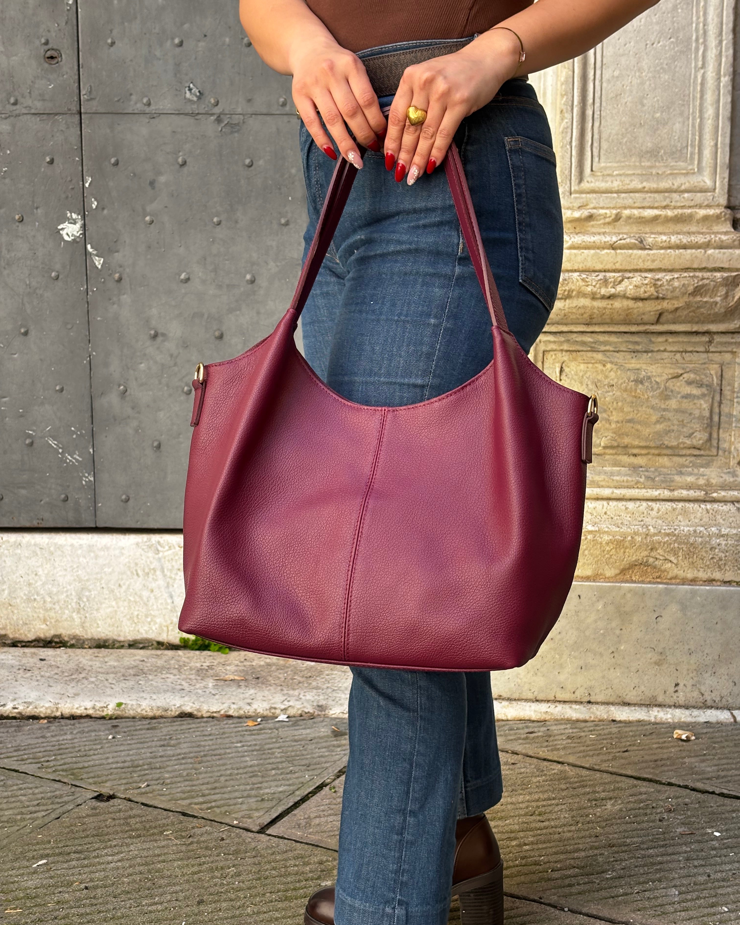 Borsa LOLA in vera pelle martellata, capiente ed elegante, con dettagli in acciaio inox dorato. Dotata di chiusura con zip, interno foderato con tasca interna e tracolla regolabile in vera pelle, è perfetta per un look raffinato e pratico ogni giorno. ALAINCOX Genova Via di fossatello 